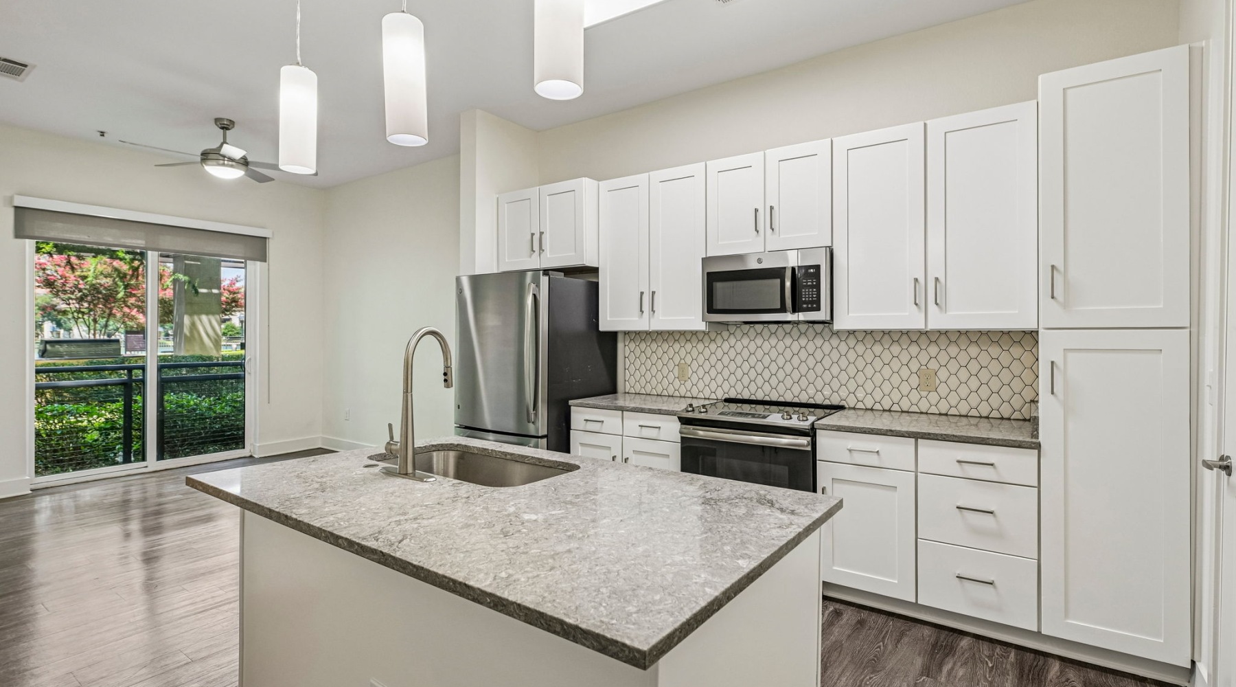 Elevated apartment kitchen at The Banks at Las Colinas featuring white shaker cabinets, quartz countertops, stainless steel appliances, and a spacious kitchen island.